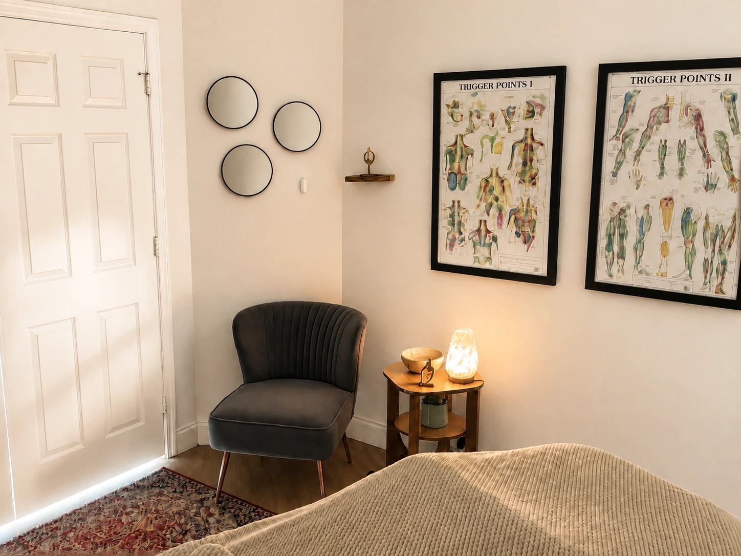 The treatment room's reading chair and trigger point charts beside the massage table.