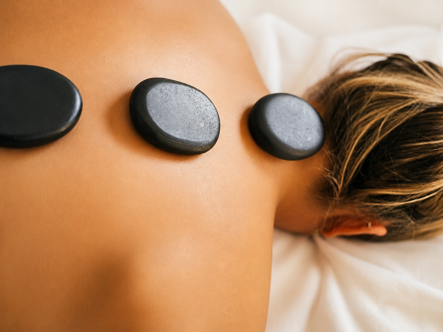 Heated basalt stones placed along a client's shoulder.
