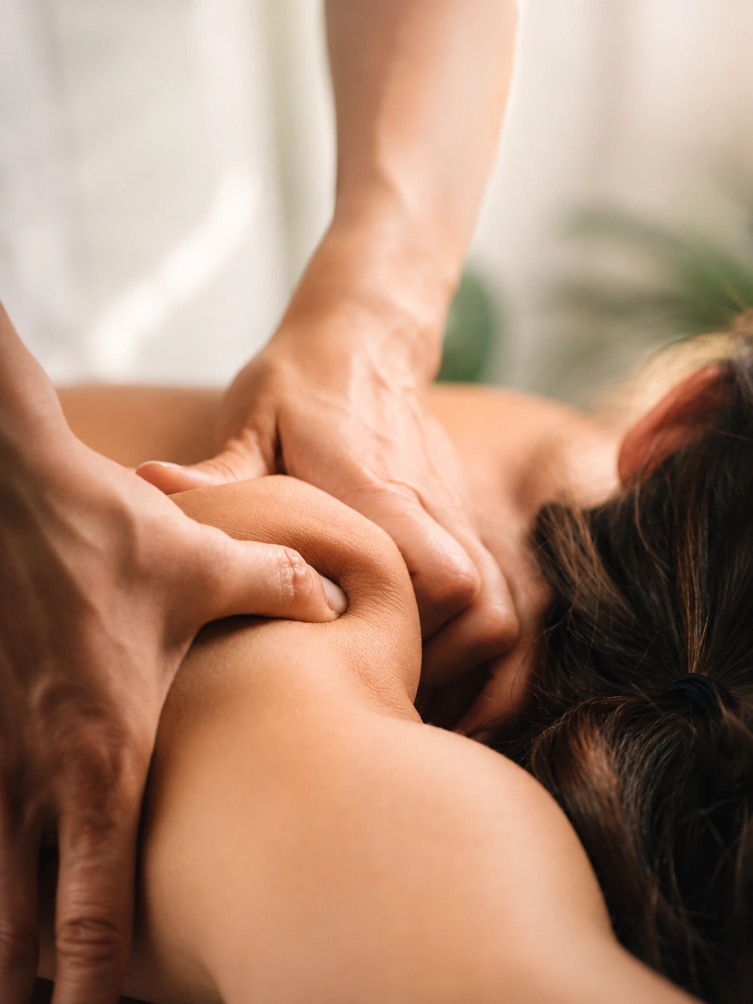 A therapist working deeply into a client's shoulder.